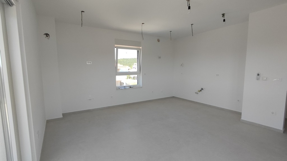 Světlý obývací a kuchyňský kout s okny a potrubím