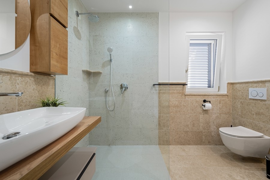 Moderní koupelna se sprchovým koutem a toaletou v úrovni podlahy