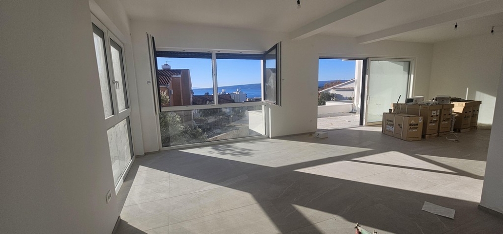 Obývací pokoj s velkými okny a výhledem na moře