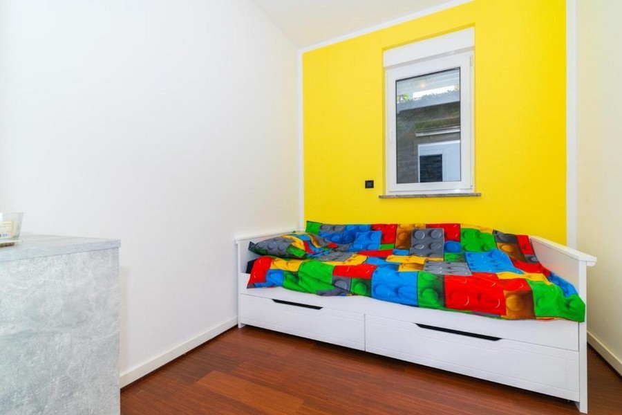 Druhá ložnice s jednolůžkem a barevnou stěnou