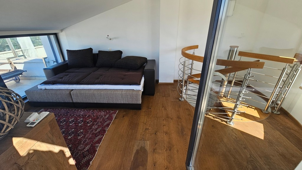 Galerie s pohovkou a točitým schodištěm do nižší úrovně