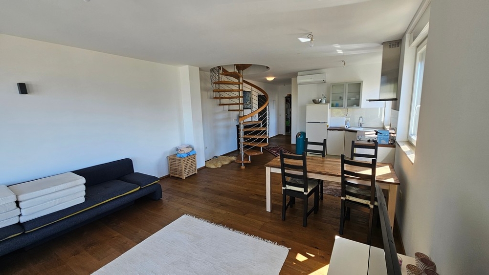 Otevřený obývací a jídelní kout s kuchyní a točitým schodištěm