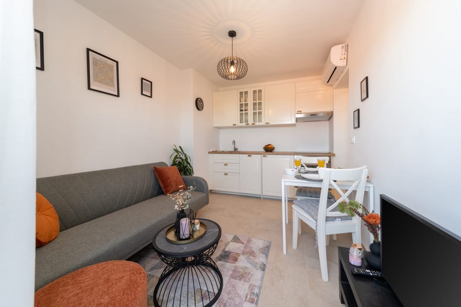 Obývací pokoj s pohovkou, stolem a otevřenou kuchyní