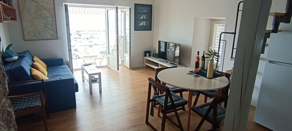 Obývací pokoj s pohovkou, jídelním stolem a balkonem s výhledem na moře