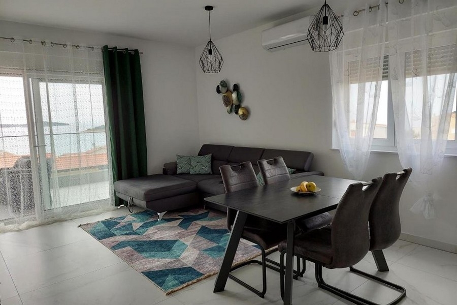 Obývací pokoj s pohovkou, jídelním stolem a výhledem na moře přes velké přední okno