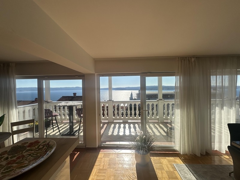 Obývací pokoj s velkým oknem a vstupem na balkon s výhledem na moře