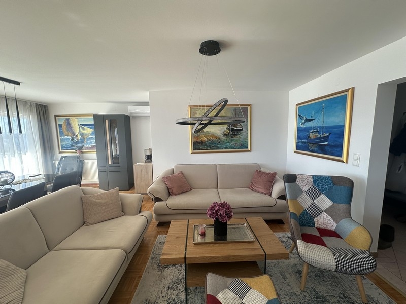 Světlý obývací pokoj s pohovkou, konferenčním stolkem a nástěnnými obrazy