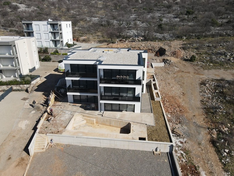 Moderní rezidenční komplex s balkony a skleněným zábradlím na přímořském místě