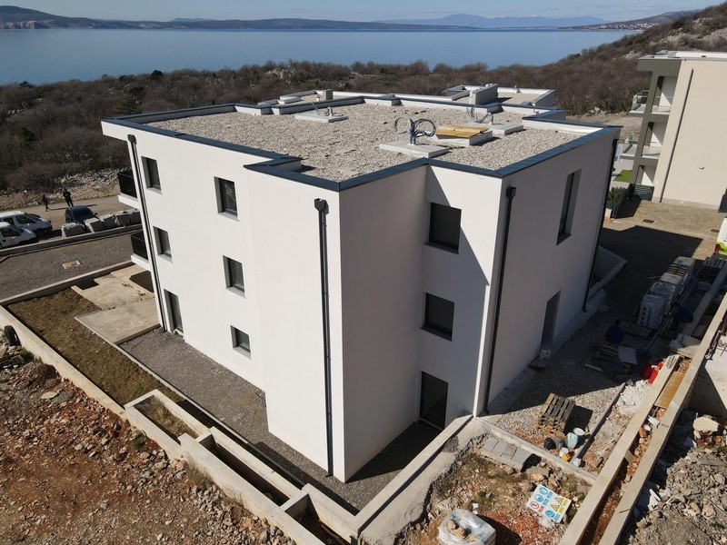 Nový bytový dům s plochou střechou a moderní architekturou v blízkosti pobřeží