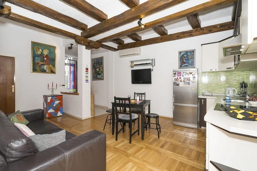 Obývací část s kuchyní a jídelním koutem a dřevěným trámovým stropem