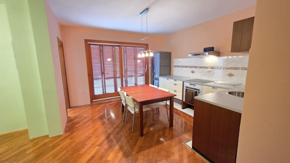 Obývací pokoj s kuchyňským koutem a jídelním stolem a vstupem na balkon