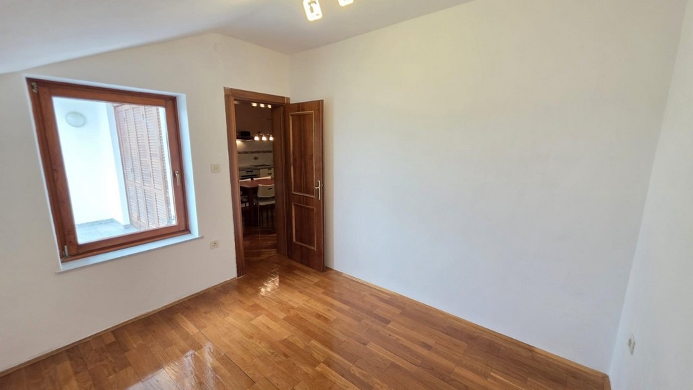 Ložnice s dřevěnou podlahou a oknem