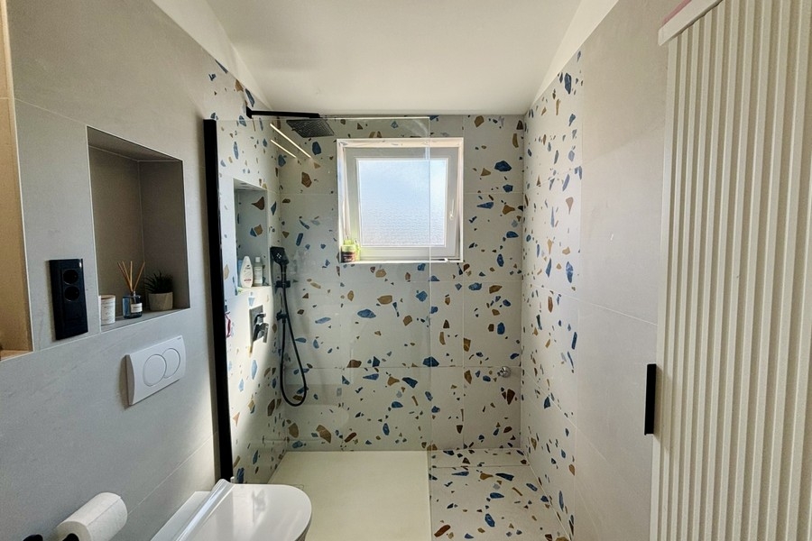 Moderní koupelna se sprchovým koutem v úrovni podlahy a oknem