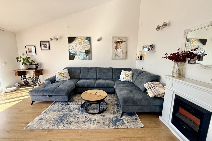 Světlý obývací pokoj s velkou pohovkou a moderním prostředím