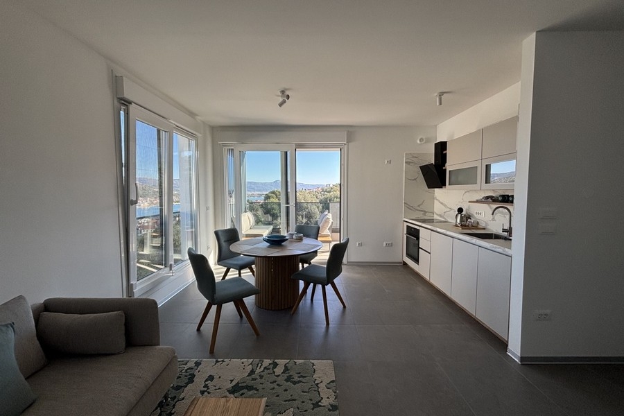 Světlý obývací pokoj s velkými okny a výhledem na moře