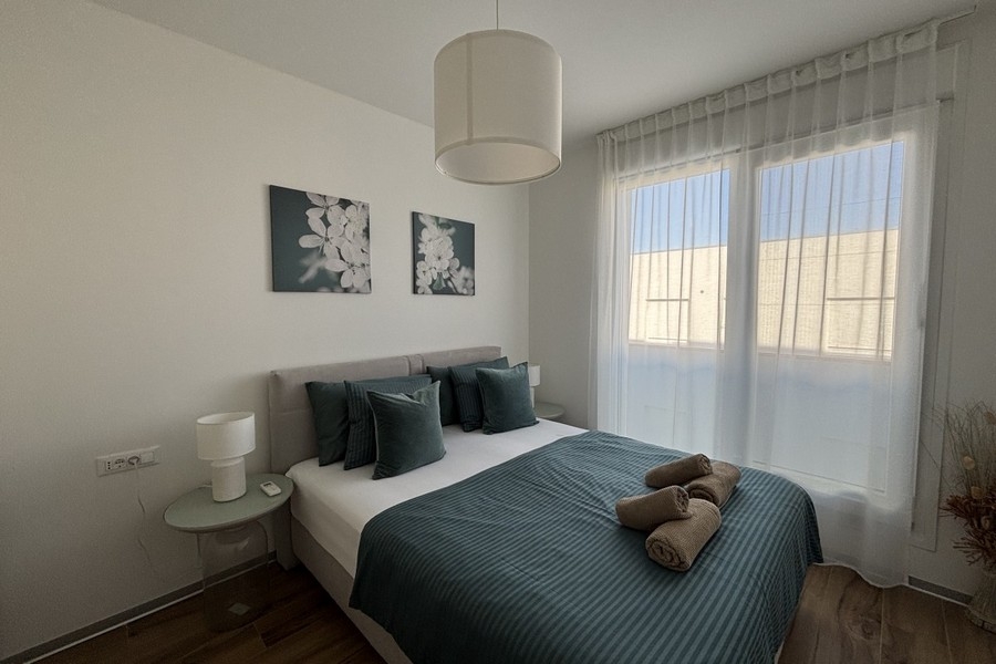 Ložnice s manželskou postelí a velkými okny