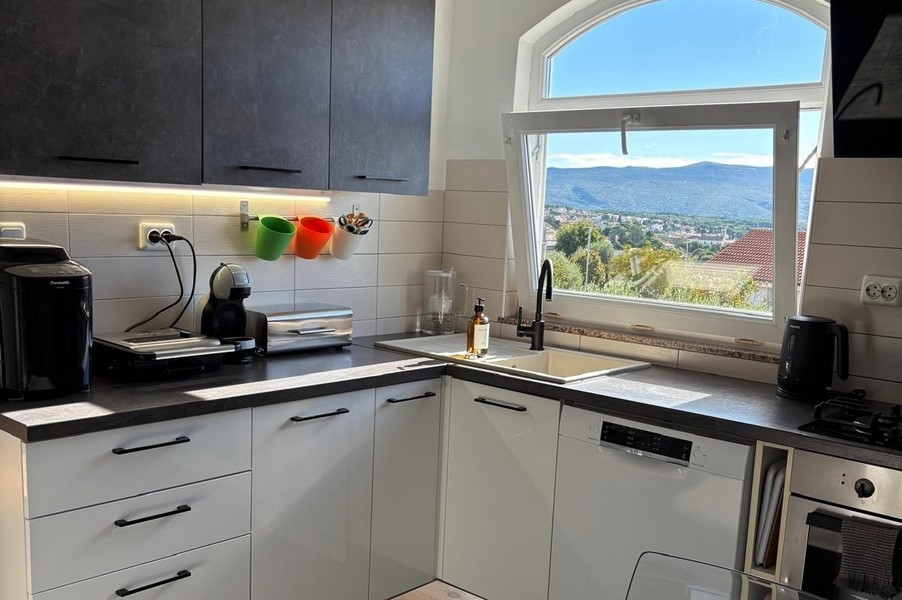 Výhled na moře z kuchyně přes střechy a pobřežní krajinu