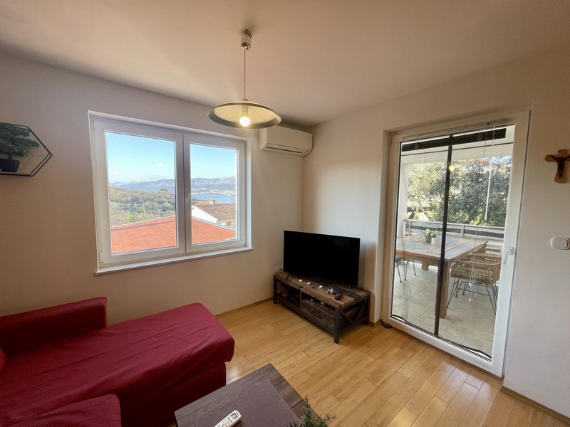 Obývací pokoj s pohovkou, TV a balkonem s výhledem na moře