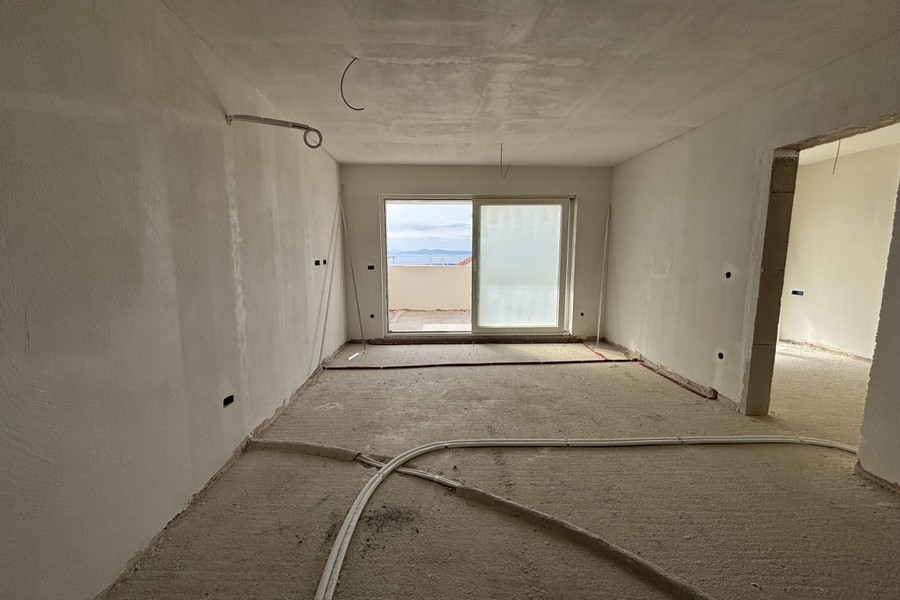 Vnitřní pohled na otevřený obývací prostor s výhledem do kuchyně a chodby