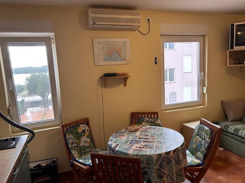 Obývací a jídelní kout s kulatým stolem a výhledem na moře z okna