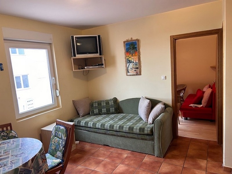 Kompaktní obývací pokoj s pohovkou, televizí a vstupem do ložnice