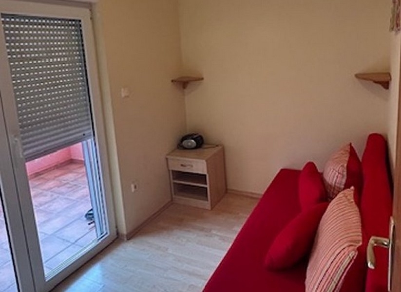 Ložnice s červenou pohovkou a vstupem na balkon