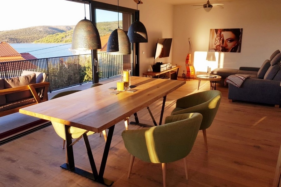 Otevřený obývací prostor s pohovkou, jídelním stolem a vstupem na balkon