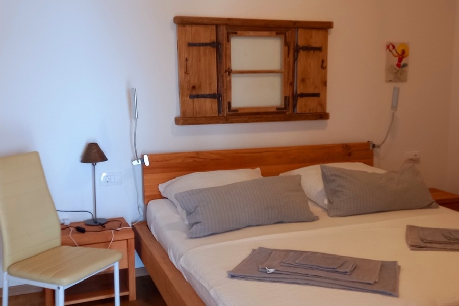 Ložnice s manželskou postelí a jednoduchým nábytkem