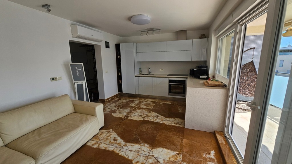 Otevřený obývací pokoj s moderně vybavenou kuchyní a vstupem na terasu