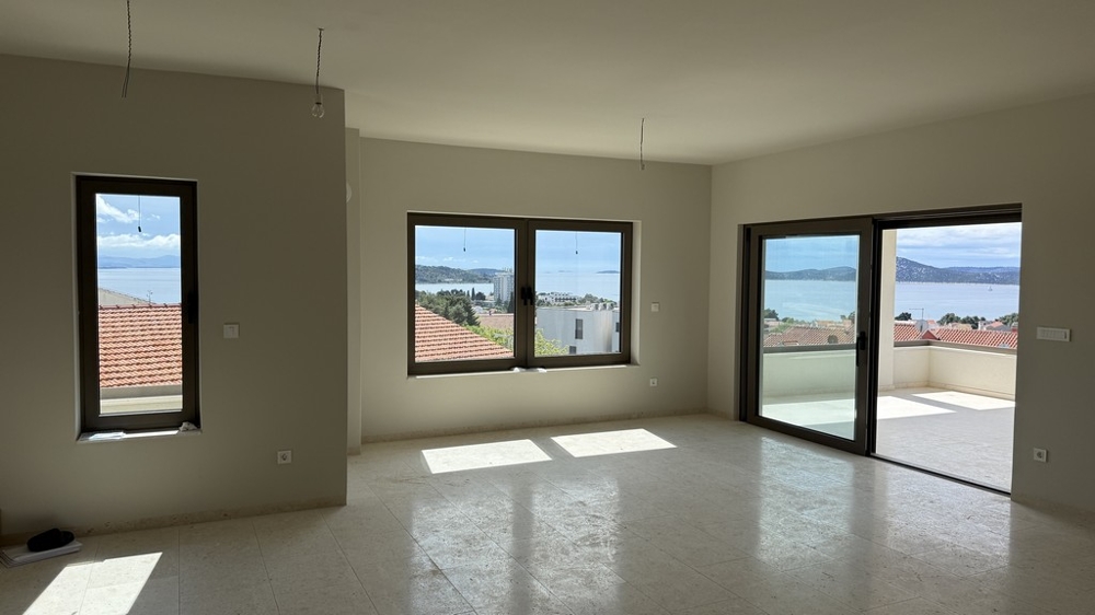 Prostorný obývací pokoj s panoramatickými okny a výhledem na moře