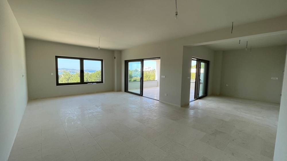 Světlý otevřený obývací pokoj s velkými okny a výhledem na moře