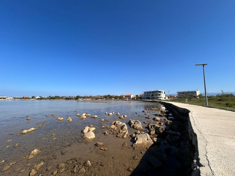 Pobřeží s promenádou a čistým mořem v Privlaka