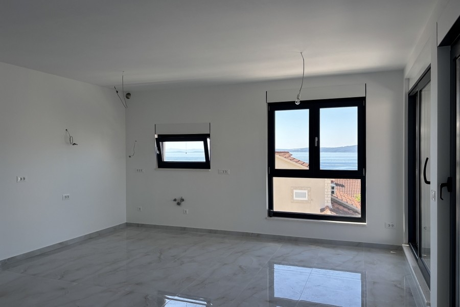 Otevřený obývací pokoj se vstupem na balkon a výhledem na moře