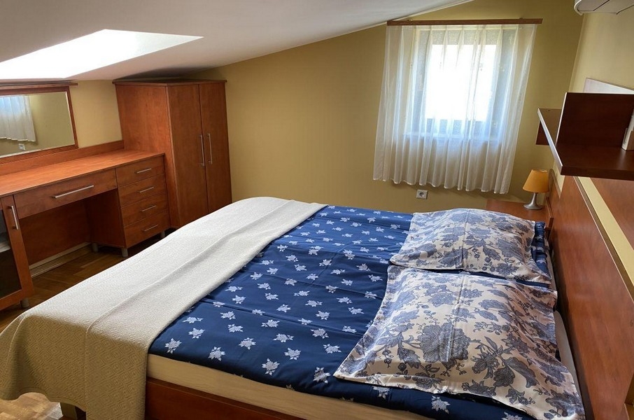 Ložnice s manželskou postelí a střešním oknem v apartmánu na Krku
