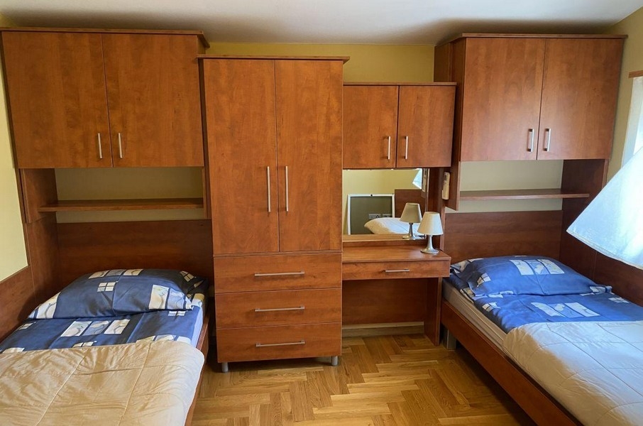Ložnice s jednolůžky a dřevěným nábytkem v apartmánu