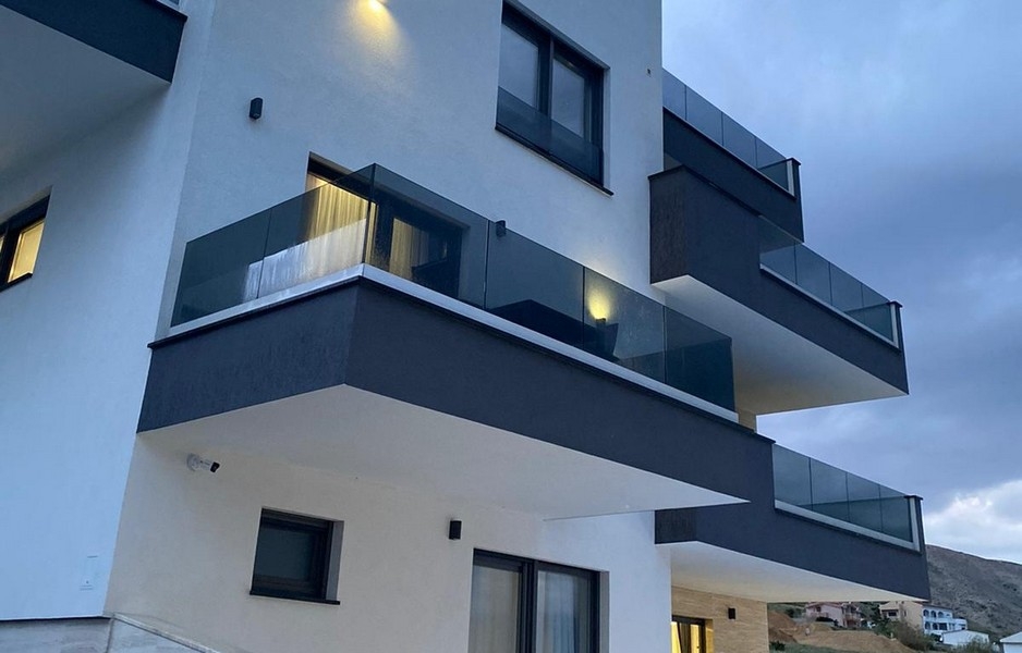 Moderní obytná budova s ​​balkony a skleněným zábradlím na Pagu