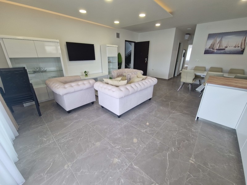 Otevřený obývací prostor s kuchyní a výhledem na moře v moderním apartmánu