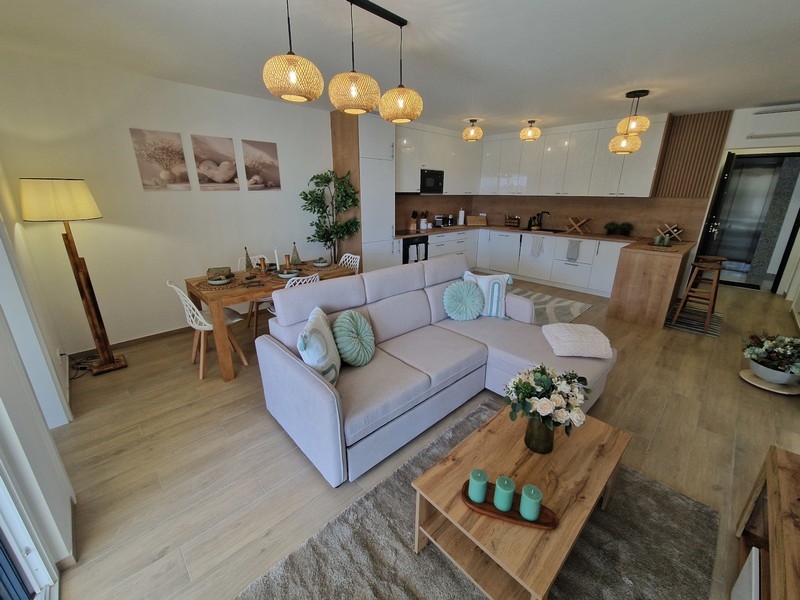 Světlý obývací pokoj s moderně zařízenou kuchyní