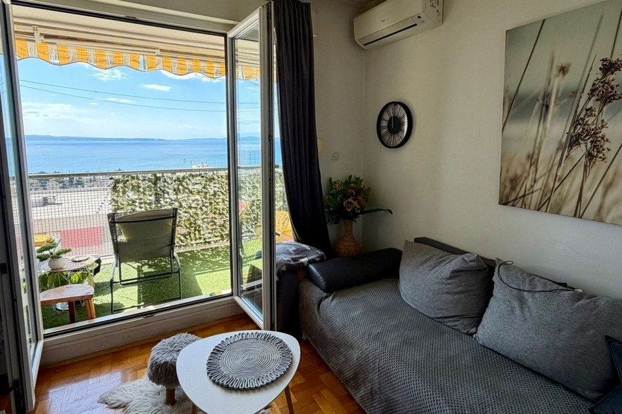 Světlý obývací pokoj s klimatizací a vstupem na balkon