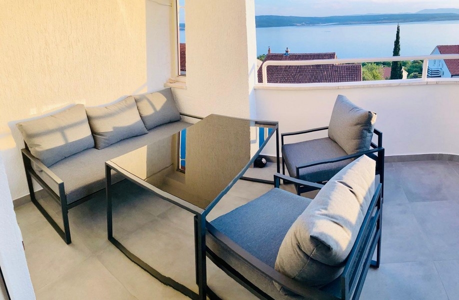 Balkon s obývacím nábytkem a výhledem na moře