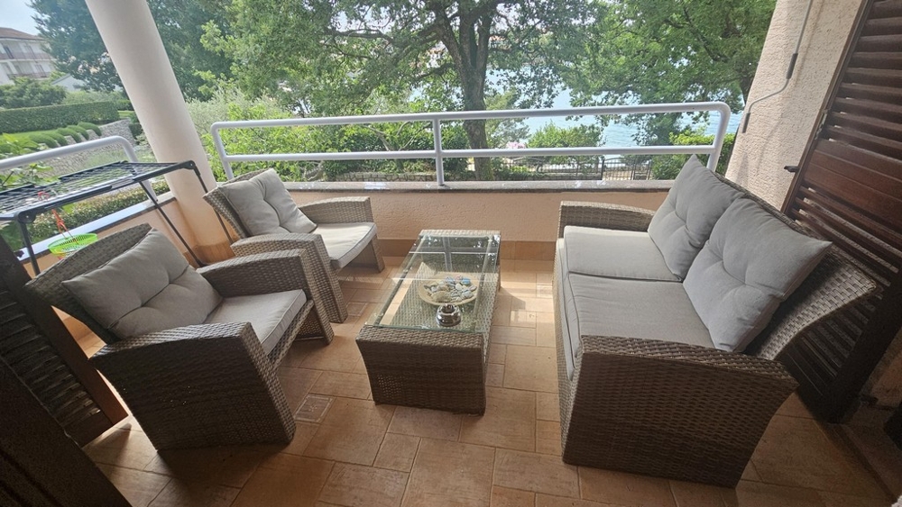 Krytý balkon s obývacím nábytkem a výhledem na moře
