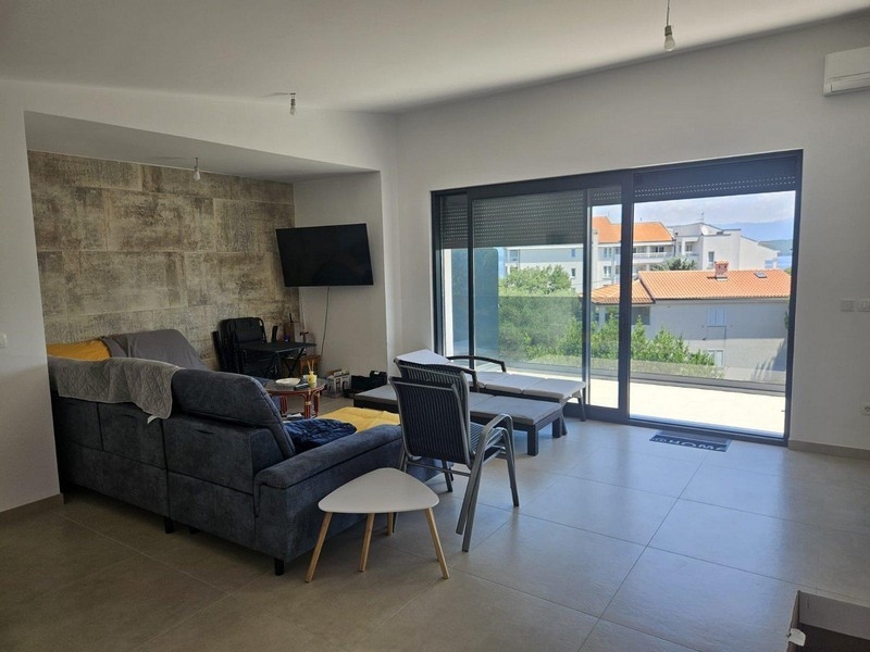 Obývací pokoj se sedací soupravou, stěnou z přírodního kamene a vstupem na balkon