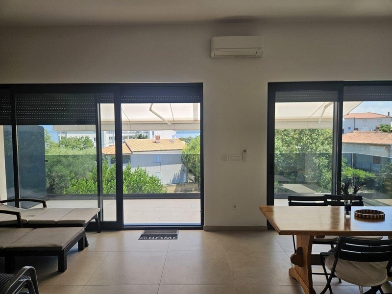 Jídelna s dřevěným stolem a výhledem na balkon a moře
