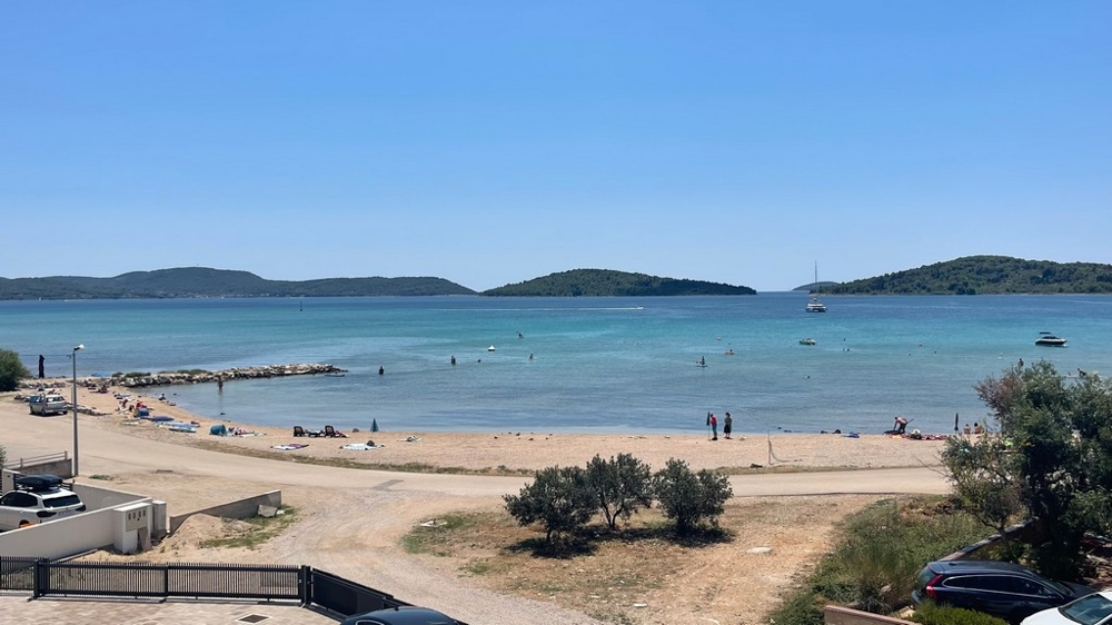 Oblázková pláž a výhled na moře před novou budovou ve Srimě u Vodice