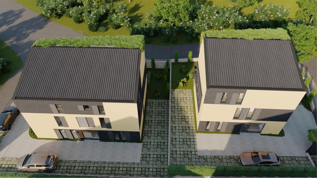 Letecký snímek dvou budov se zelenými střechami a parkovacími místy