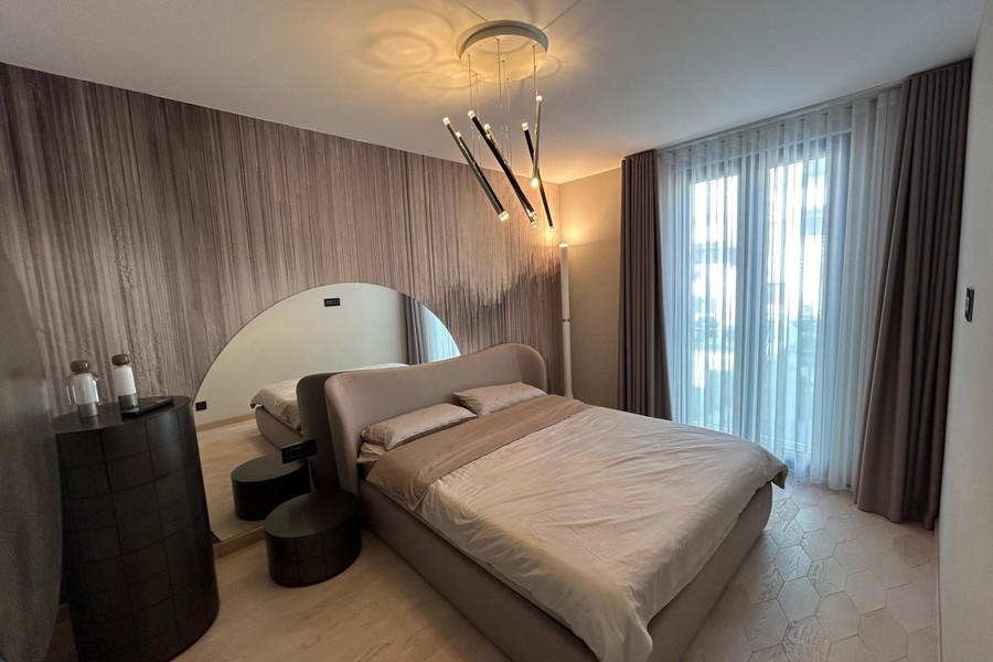 Ložnice s čalouněnou postelí a designovým svítidlem