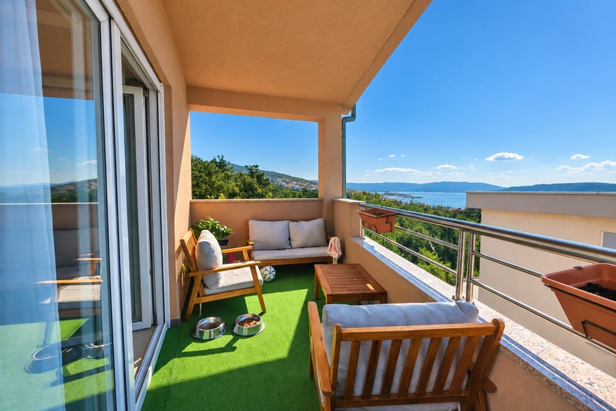Balkon s dřevěným nábytkem a výhledem na moře