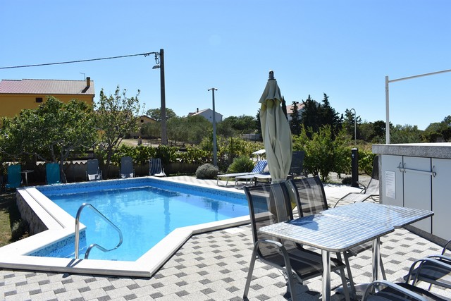 Pohled ze salonku na bazén a zahradu v Chorvatsku.