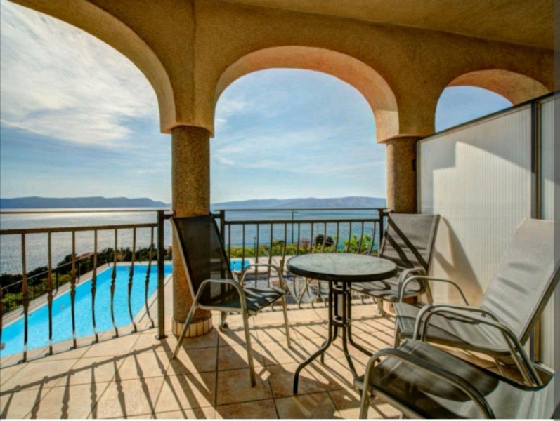 Výhled na bazén a moře z kryté terasy v patře.