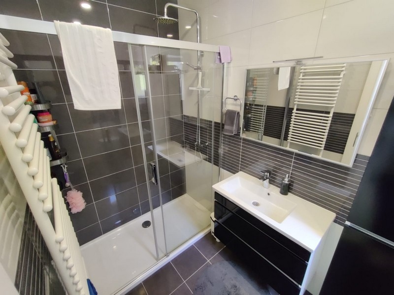 Koupelna s hnědými obklady a sprchovým koutem.